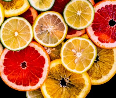 Colorful citrus fruit slices arranged against a black background, showcasing variety and freshness.