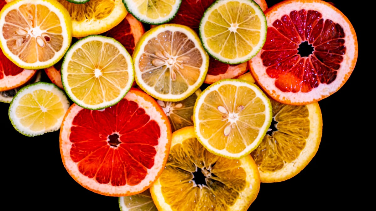 Colorful citrus fruit slices arranged against a black background, showcasing variety and freshness.